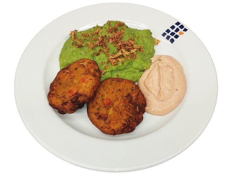 "Ein Teller mit zwei goldbraunen Frikadellen, einer Portion grünem Guacamole mit gerösteten Nüssen und einer Kugel hellbrauner Dip-Sauce."