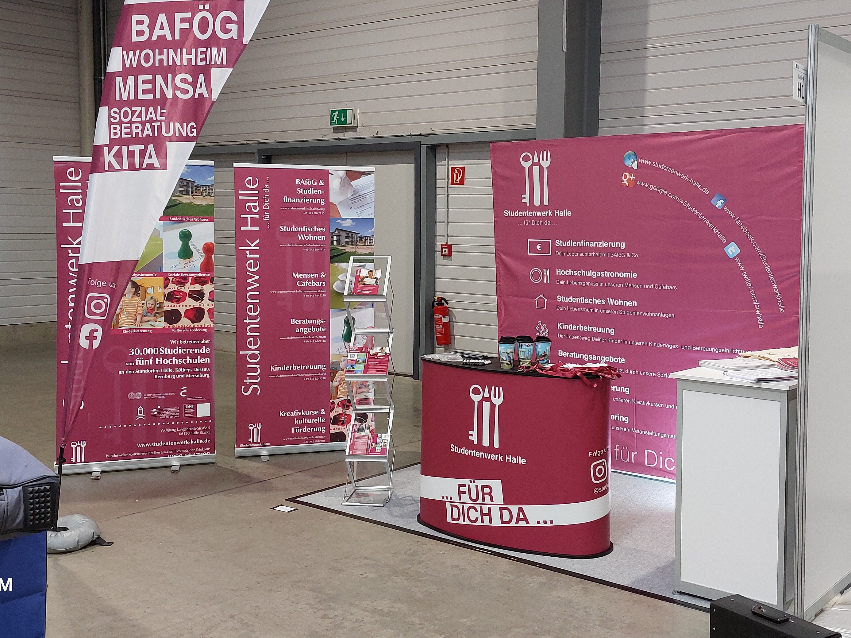 Ein Messe- oder Informationsstand mit Plakaten und Flyern zu Themen wie BAföG, Wohnen, Mensa und Kita. Der Stand ist mit einem roten Tisch und Informationsmaterial ausgestattet. Die Veranstaltung findet am 22. Februar 2024 statt.