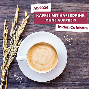 "Ab 2024: Kaffee mit Haferdrink ohne Aufpreis in den Cafebars. Ein Bild zeigt eine Tasse Kaffee mit Hafermilchschaum und Haferhalmen daneben auf einem Holztisch."