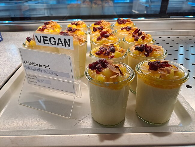 Vegane Grießbrei-Portionen in kleinen Gläsern mit karamellisierter Topping-Dekoration, serviert auf einem Tablett.