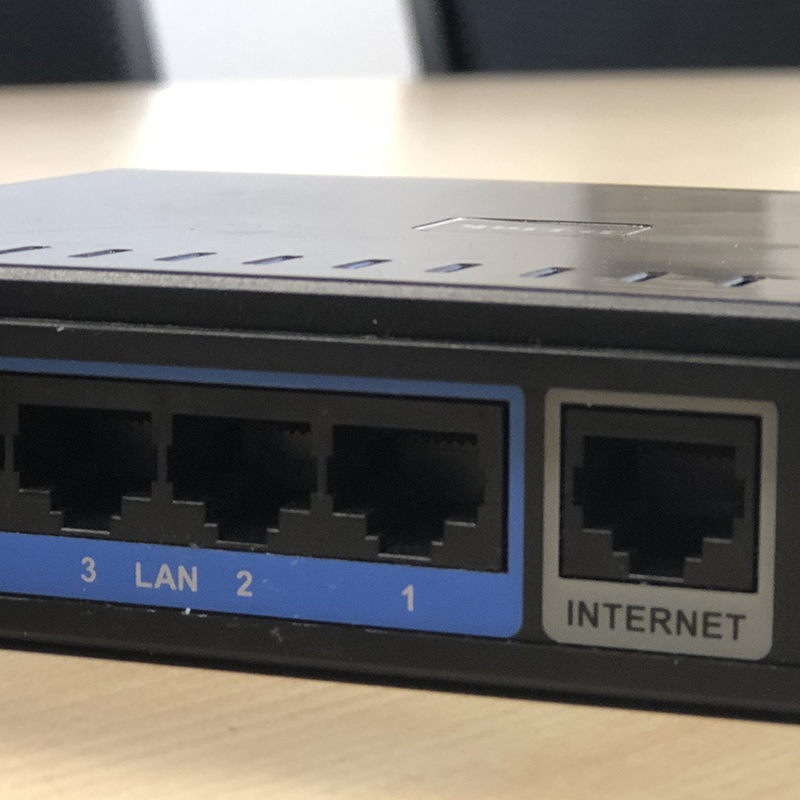 Ein Router mit vier Anschlüssen: drei blaue LAN-Ports (1, 2, 3) und ein grauer Internet-Port. Die Anschlüsse sind für die Verbindung von Geräten und dem Internet vorgesehen.